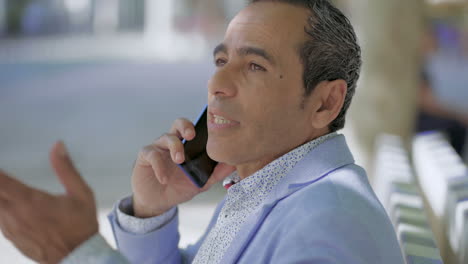 hombre de mediana edad hablando por teléfono móvil al aire libre