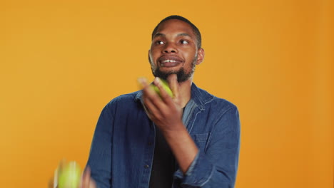 playful person juggling in the studio with ripe green apples