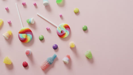 video of colourful various sweets on pink background