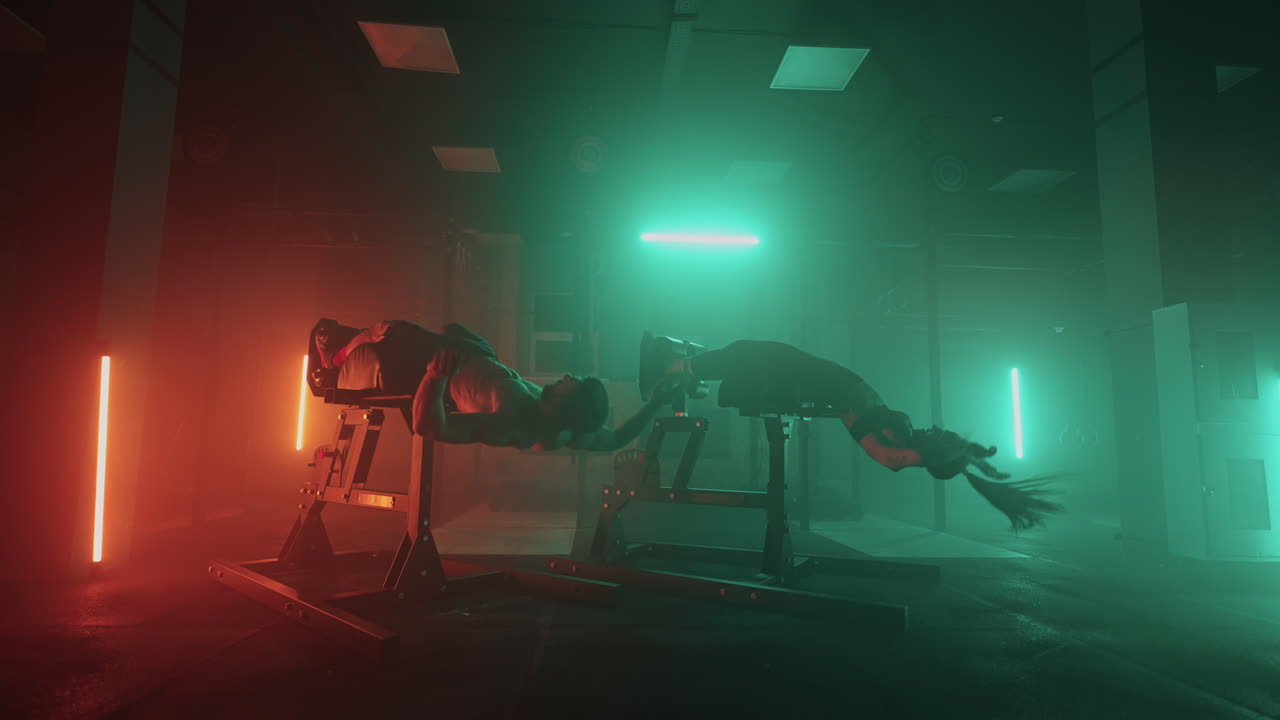 남자와 여자가 체육관에서 함께 몸을 들어 올리는 복부 운동을 합니다. 두 사람이 함께 복부 운동를 합니다.