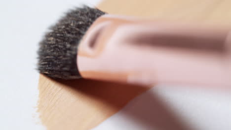 brushing a layer of make-up foundation on a clean, white palette board to check its texture and tone