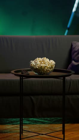 vertical video bowl of popcorn on table in neon illuminated home theater apartment