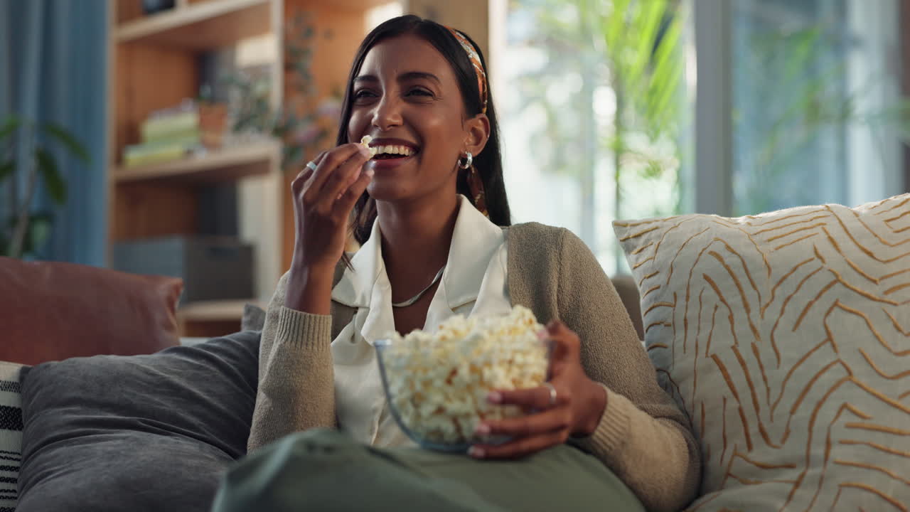 Donna che mangia popcorn mentre guarda la TV a casa