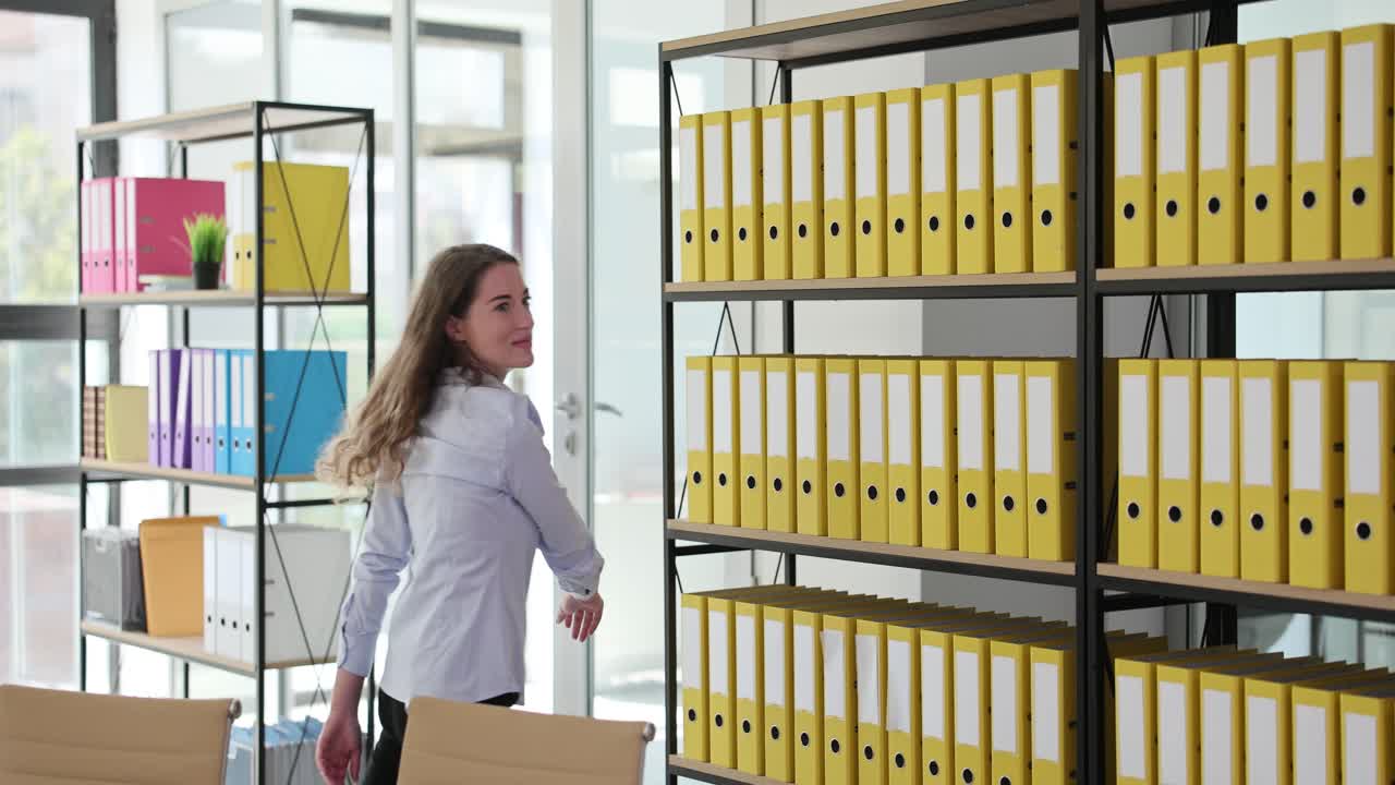 Woman in office next to shelves with folders