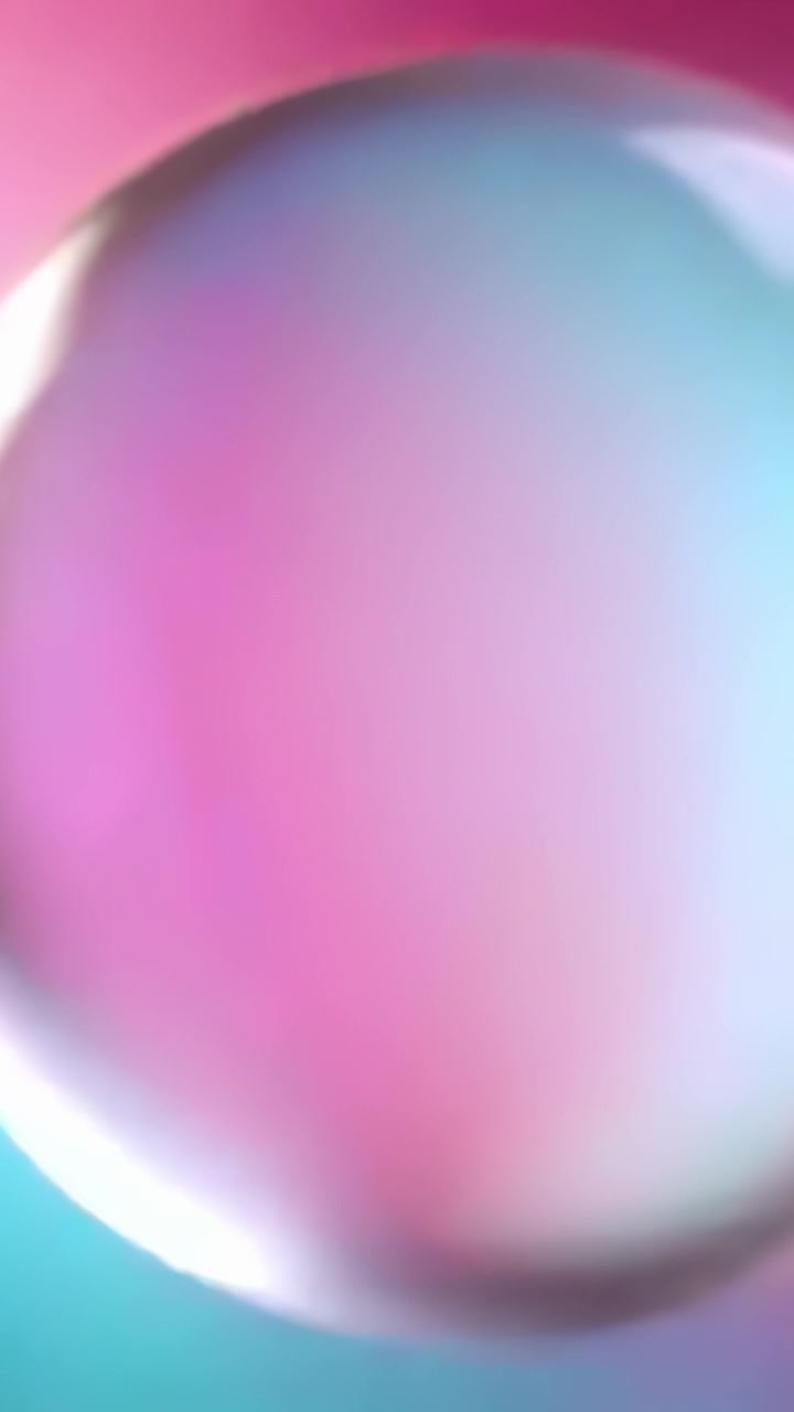 Vertical video: Drifting orb reacting to light shift rotating closer over magenta-cyan rim glinting