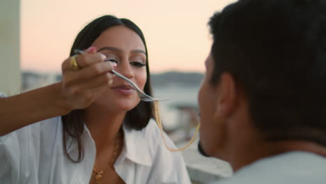 adorable couple tasting spaghetti sunset view closeup. newlyweds kissing eating