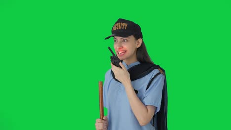 Happy-Indian-female-security-guard-talking-through-walkie-talkie-Green-screen