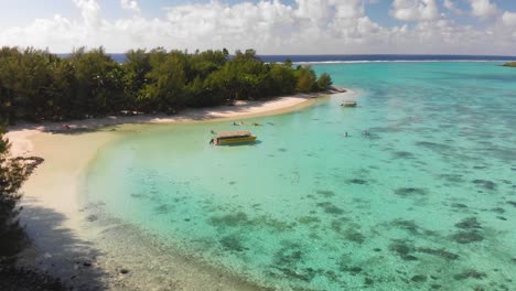 Flying-above-tourists-kayaking-in-the-idyllic-Muri-lagoon,-strolling-around-the-paradise-island-with-gorgeous-white-sand-beaches-and-lush-palm-trees