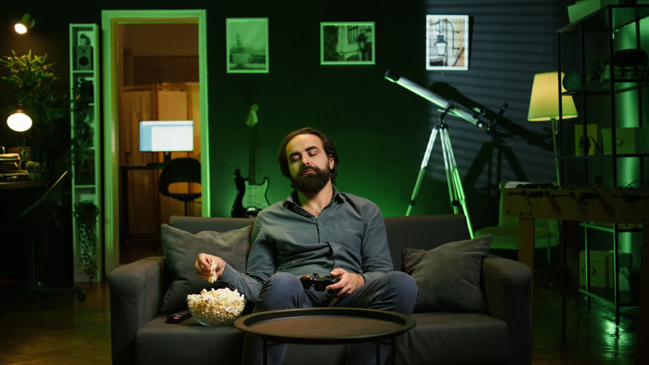 Jogador entediado jogando em console de TV usando gamepad, comendo pipoca