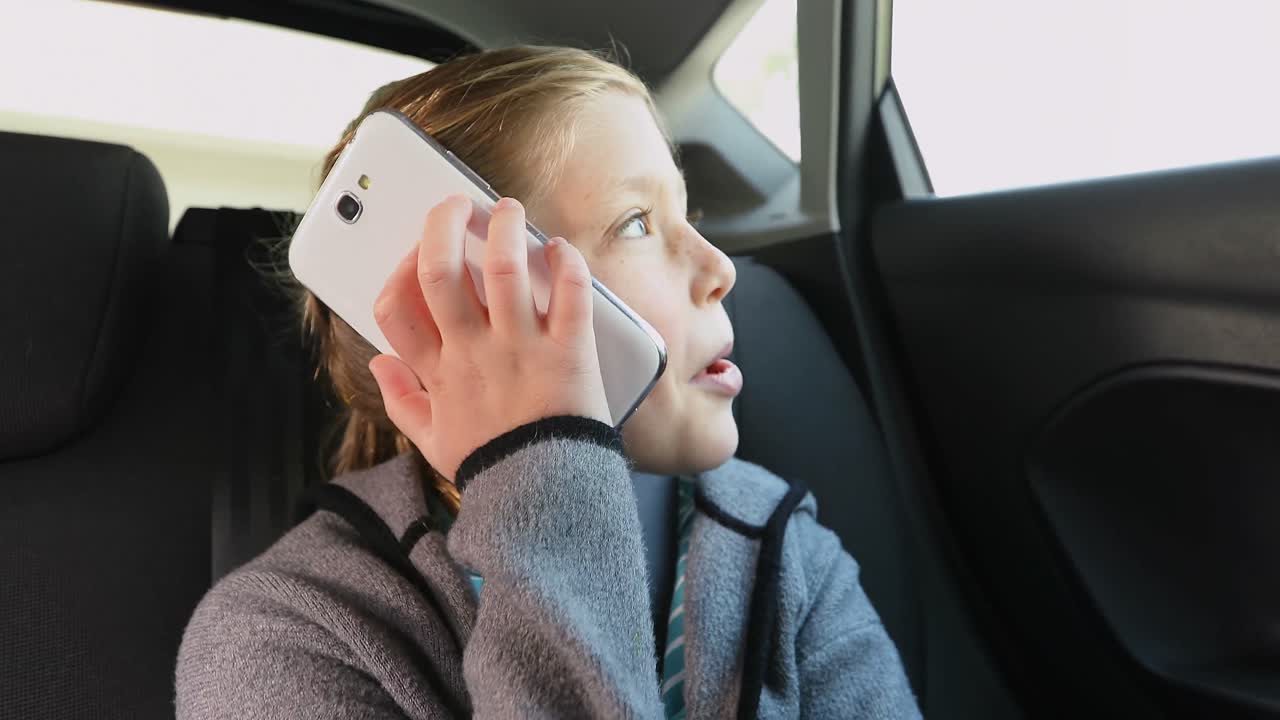 Glückliches kleines Mädchen telefoniert, während es im Auto sitzt 4K 4k