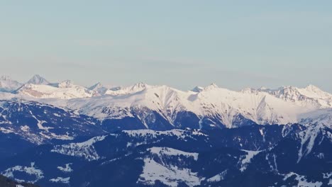 aerial drone view capturing the silhouette of snow-covered mountains at sunrise