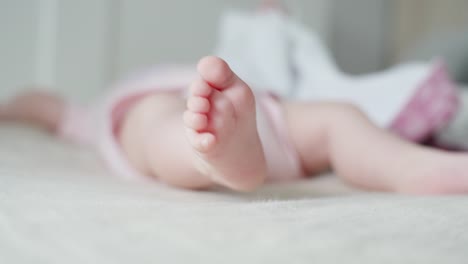 Baby-Lying-on-Bed,-Curling-Toes-while-Moving-Feet,-Selective-Focus