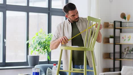 furniture-restoration,-diy-and-home-improvement-concept--man-with-ruler-measuring-old-wooden-chair-for-renovation