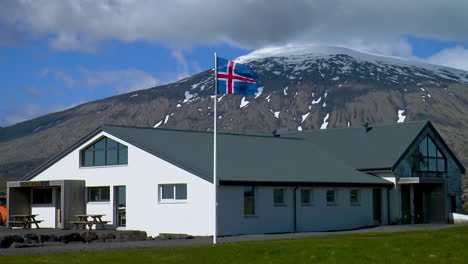 big, classic icelandic house with iceland flag fluttering in the wind with a view of snaefellsjokull glacier and stapafell mountain in iceland on snaefellsnes peninsula