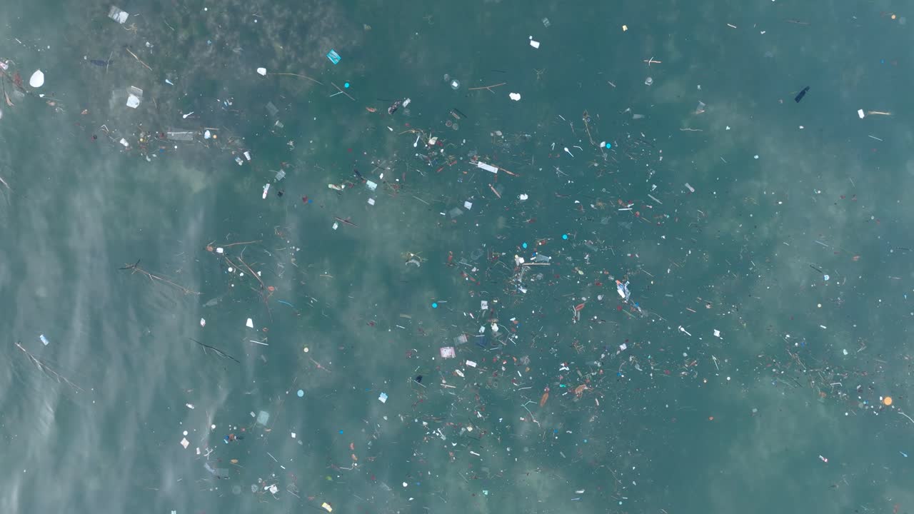 Top down drone shot of polluted water filled with plastic trash and dead coral reef in the turqouise tropical water of Balangan Beach Uluwatu Bali Indonesia