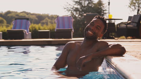 Portrait-Of-Smiling-Man-On-Summer-Holiday-Or-Vacation-Relaxing-In-Swimming-Pool