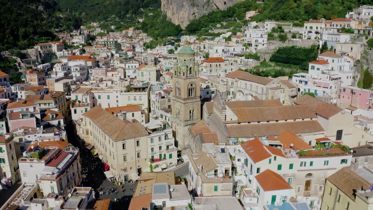 Video aereo con drone del campanile della Cattedrale nel centro di Amalfi. Architettura italiana storica con edifici bianchi sulla Costiera Amalfitana in una soleggiata giornata estiva