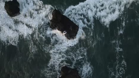 Powerful-ocean-waves-splash-onto-dark-volcanic-rocks-along-Bali-coast