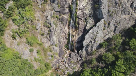 Inclinación-Aérea-Hacia-Arriba-Majestuosa-Cascada-En-El-Acantilado-De-Piedra,-Frecha-Da-Mizarela---Portugal