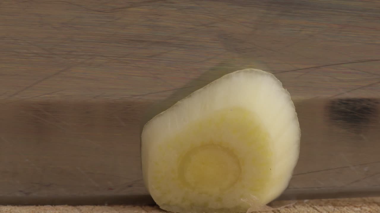Close up macro view, knife cutting, slicing a Garlic in a wooden table, cooking