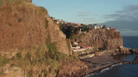 Tranquila-Y-Serena-Ciudad-Costera-Junto-Al-Océano-Lentamente-Revelada-Detrás-De-La-Montaña-Durante-La-Puesta-De-Sol-En-Ponta-Do-Sol,-Madeira,-Portugal