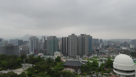 Aerial-shot-flying-over-Namsan-Park-with-Seoul-city-skyline-in-South-Korea