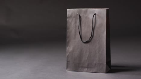 Black-gift-bag-with-black-handles-on-dark-grey-background-with-copy-space