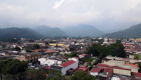 4k aerial drone footage of antigua, guatemala, with the cityscape and colorful buildings set against a backdrop of stunning mountains