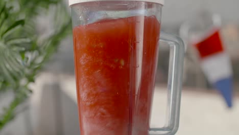 juicy red fruit smoothie spinning slow motion in blender in front of french flag shallow focus