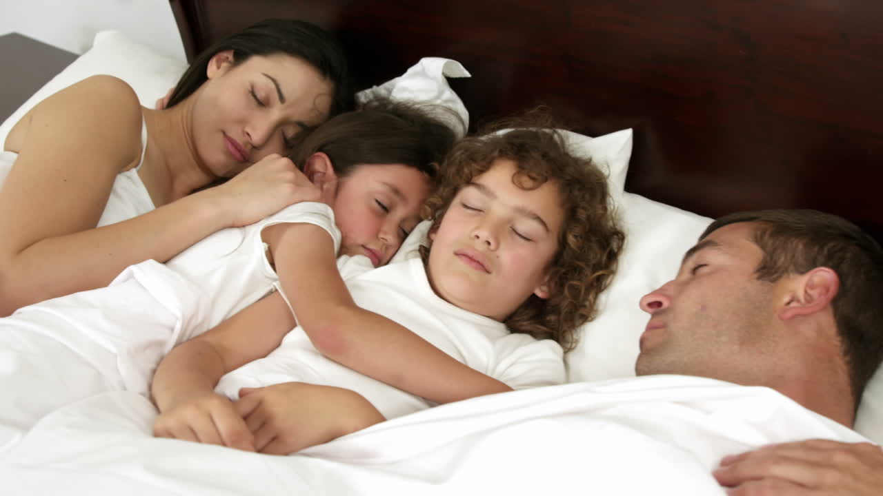 Premium stock video - Family sleeping in the same bed