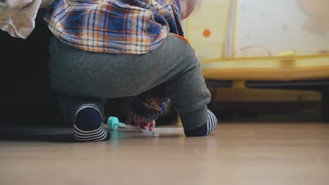 playful-baby-plays-with-nozzle-suction-at-large-bed-on-floor