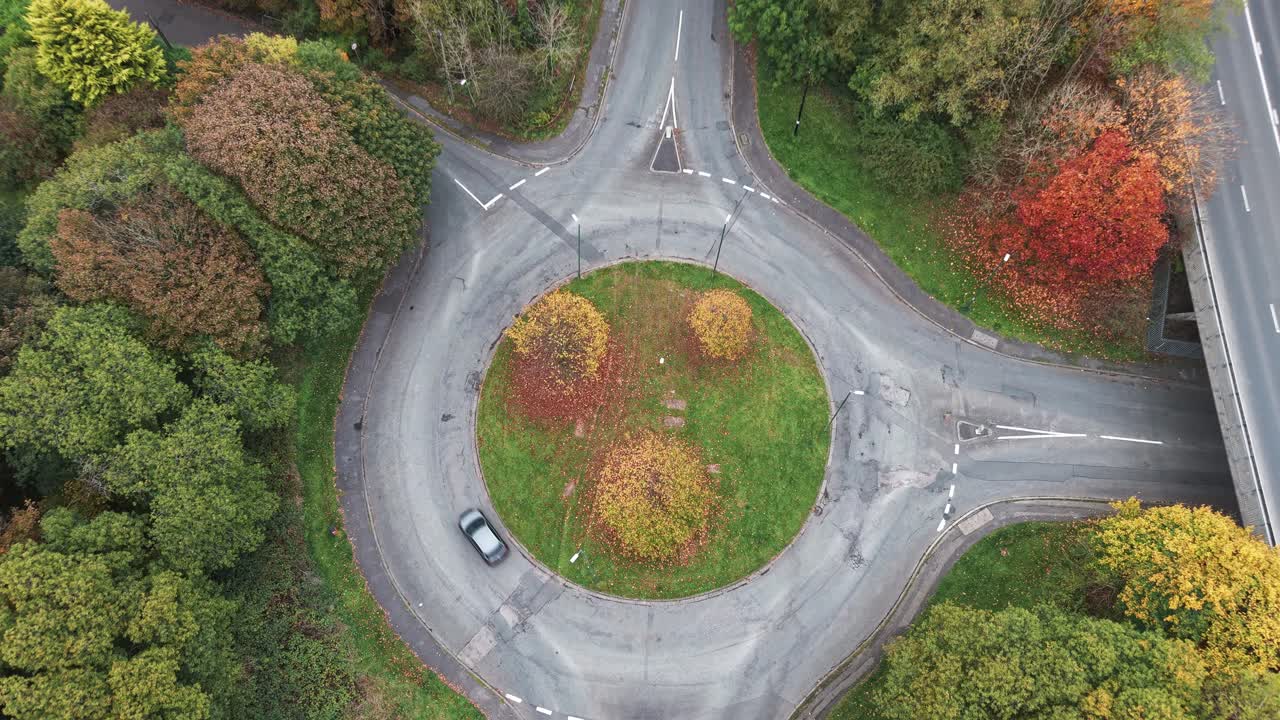 Aerial drone view of traffic roundabout surrounded by colorful autumn trees and foliage