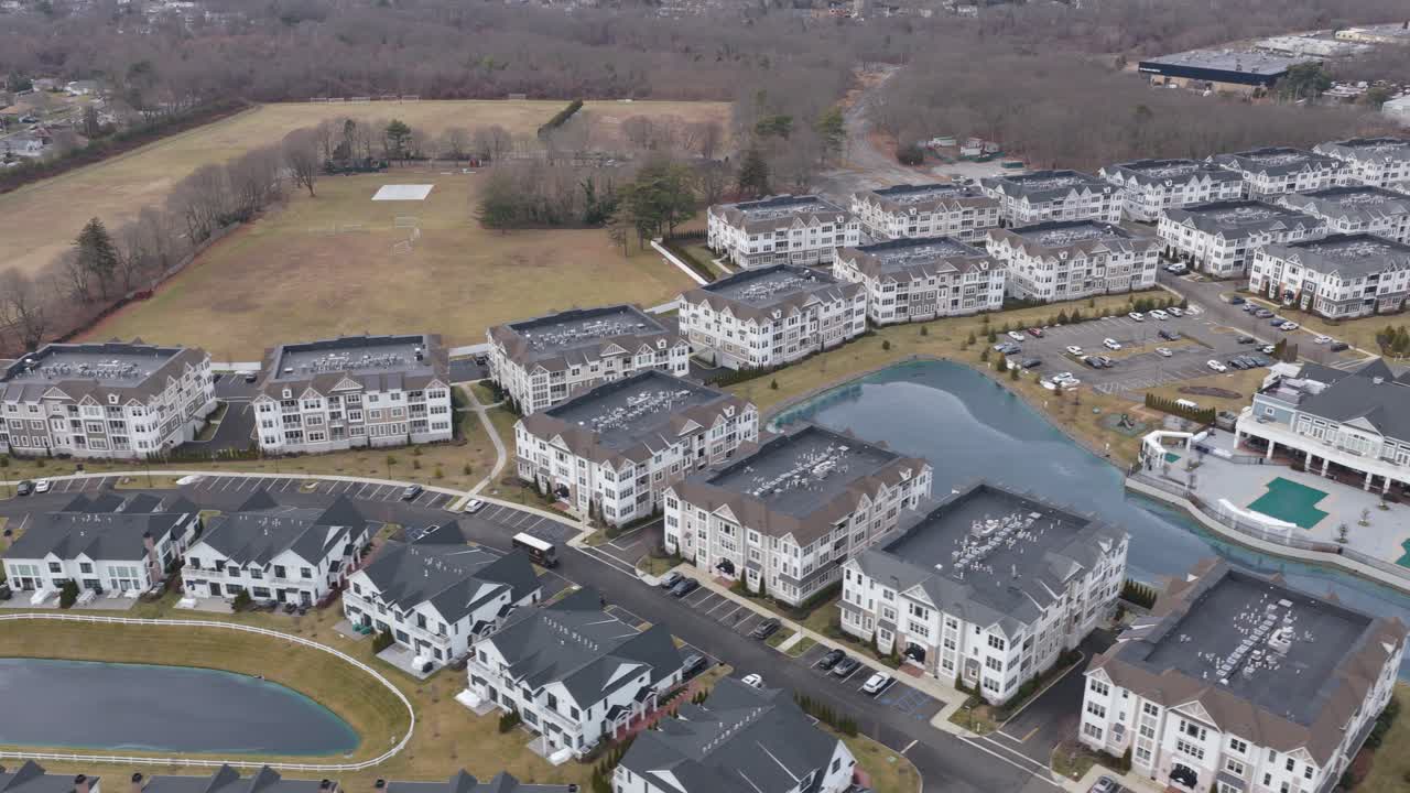 Holbrook new york high altitude perspective of a modern residential neighborhood featuring multiple apartment buildings, serene ponds, and a central clubhouse. In longisland