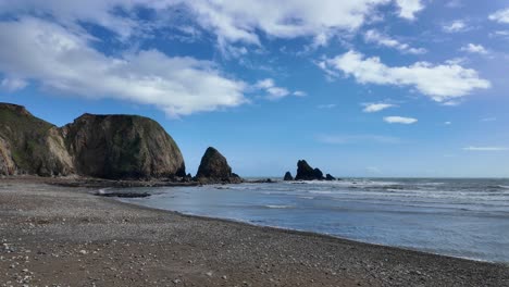 Ruhiger-Strand-Bei-Flut,-Ruhige-See-Und-Weiße-Wolken-Am-Blauen-Himmel,-Friedliche-Szene,-Waterford,-Irland