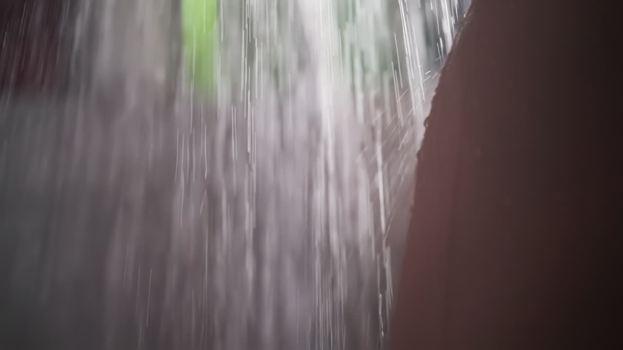 Bare woman hip and water splashes in bathroom closeup. Seductive lady washes body standing under strong shower in washroom. Hygiene routine