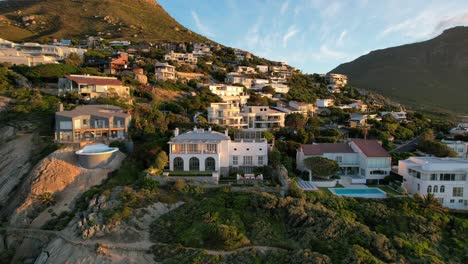 Teure-Weiße-Villen-Auf-Einer-Bergklippe-Am-Strand-Von-Llandudno,-Kapstadt,-Südafrika-Bei-Sonnenuntergang,-Luftaufnahme