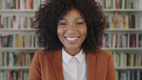 Retrato-De-Una-Joven-Y-Elegante-Mujer-De-Negocios-Afroamericana-En-Prácticas-Riéndose-Alegremente-De-La-Cámara-En-El-Fondo-De-La-Estantería-De-La-Biblioteca