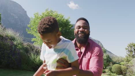 Glücklicher-Afroamerikanischer-Vater-Und-Sohn,-Die-Im-Garten-Fußball-Spielen,-In-Zeitlupe