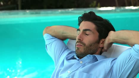 hombre de negocios relajándose en una silla de sol al lado de la piscina