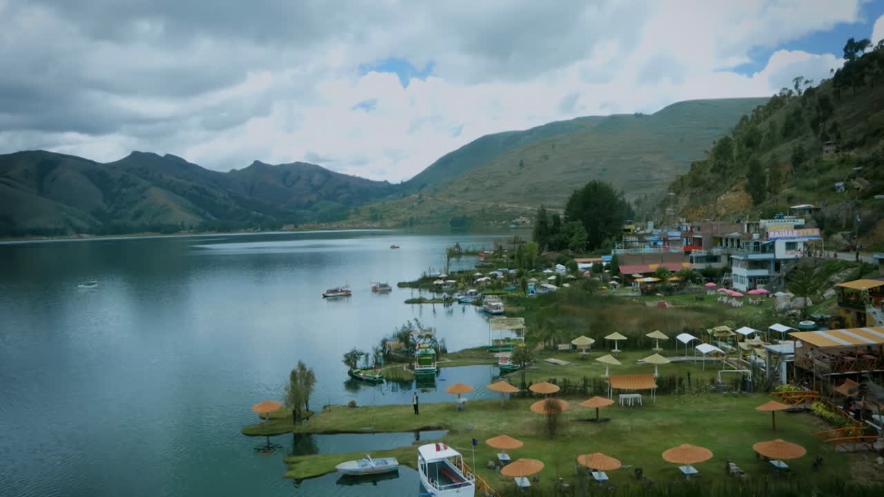 Beautiful great general shot of a community on the edge of the Amazon River in Peru with lots of vegetation and daylight. Boats floating on the river, mountains and houses around.
