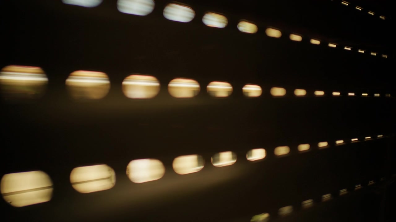 Window roller shutter partially closed, creating horizontal lines of light and shadow, forming an abstract pattern