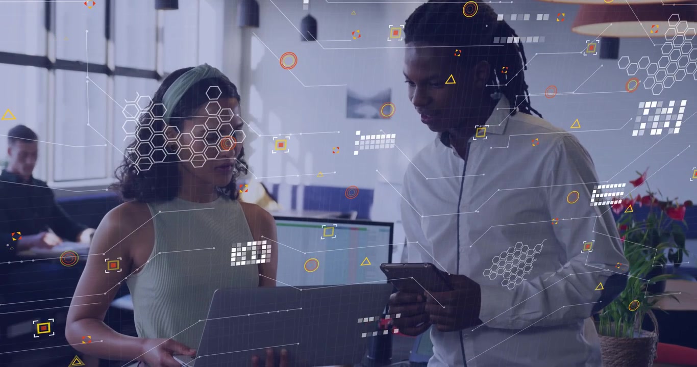 Woman presenting laptop and tablet to male coworker during tech review, sparking hex data overlay
