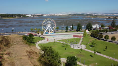 Luftaufnahme-Des-Riesenrads-Im-Park-Quinta-Dos-Franceses-Mit-Fluss-Im-Hintergrund-In-Der-Stadt-Seixal,-Portugal