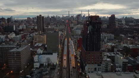 drone shot over the harlem 125th street station, towards the manhattan skyline, cloudy evening in ny, usa