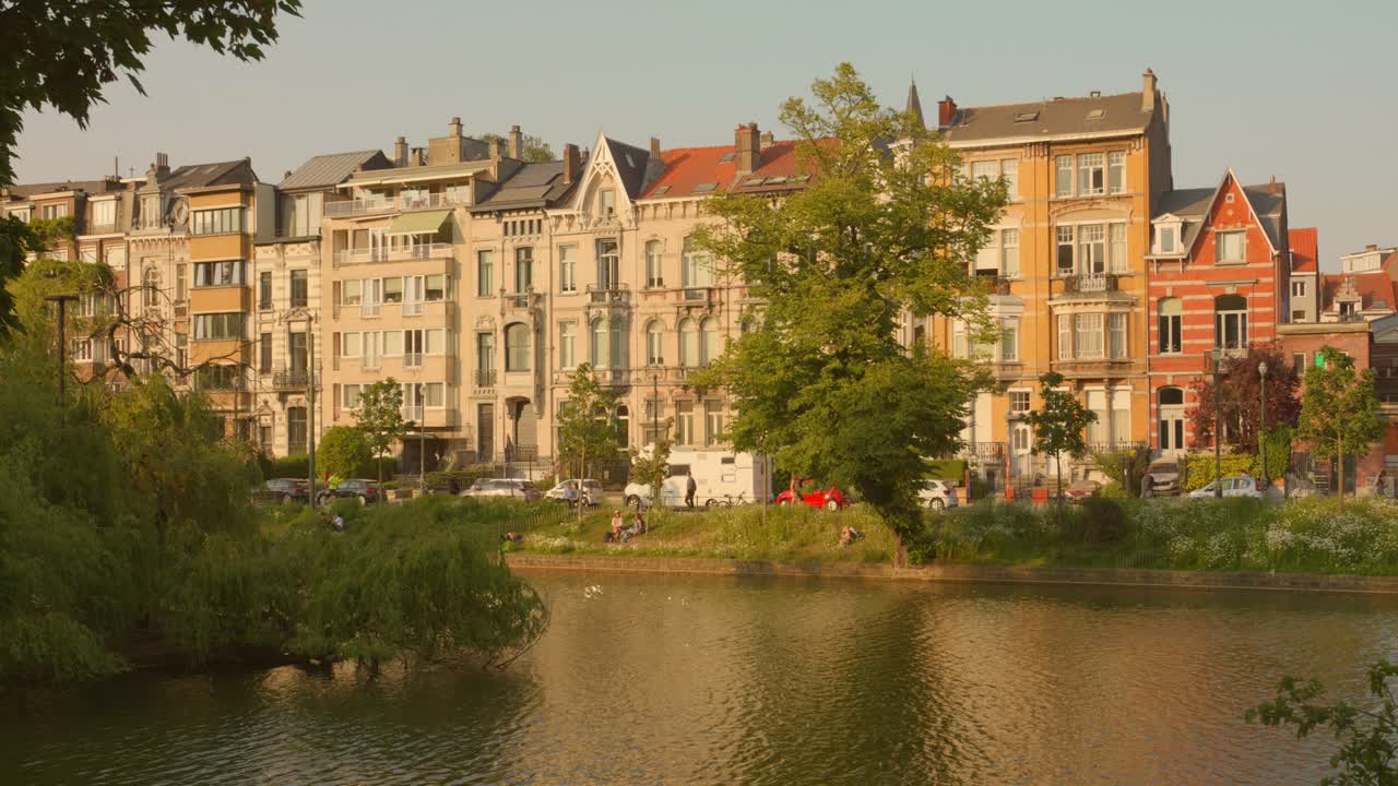 벨기에 브 ⁇ 셀 의 건물 과 아이셀스 연못 을 따라 거리 에서 운전 하는 자동차 들