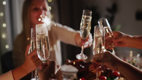 The-family-celebrates-the-New-Year-at-the-festive-table,-clinks-glasses-and-holds-sparklers-in-their-hands.