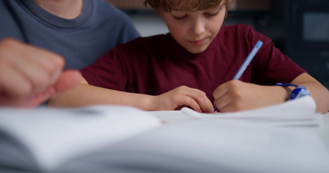 Young Boy Writing Homework with Adult Supervision