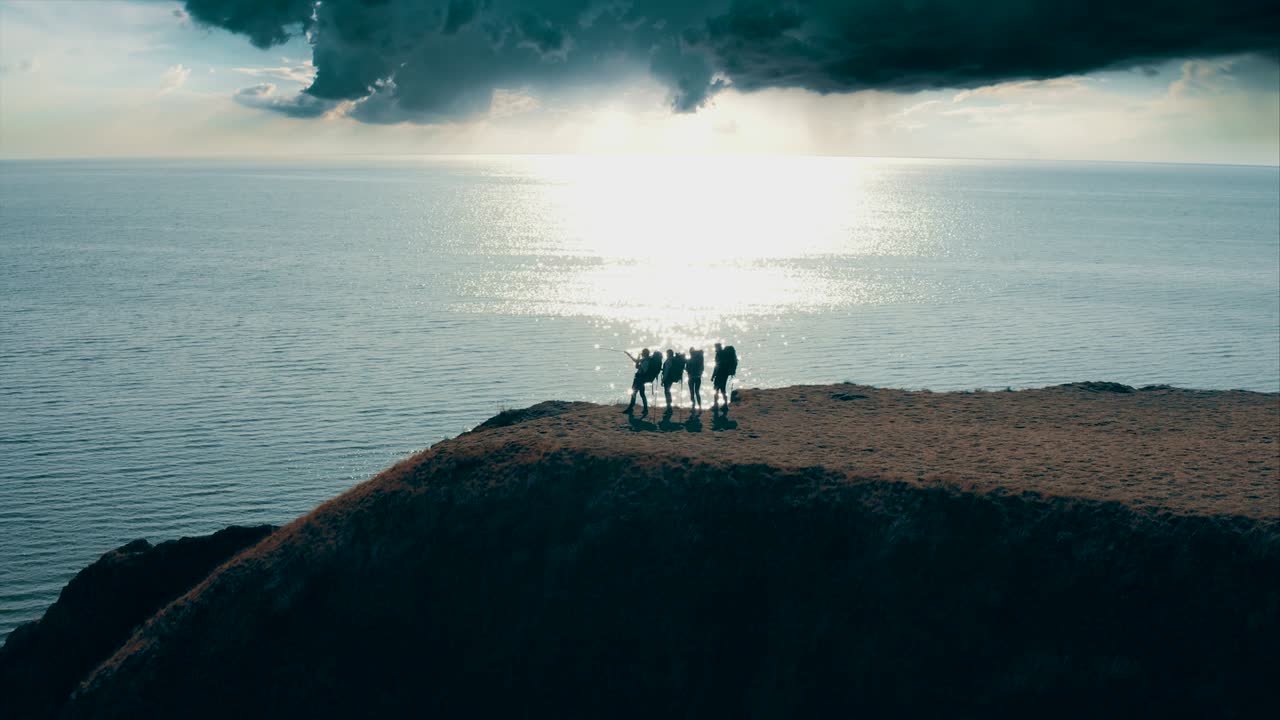 바다 근처의 산 꼭대기에 서 있는 네 명의 관광객
