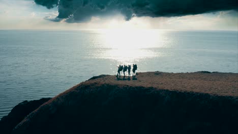 the four tourists standing on the mountain top near the sea