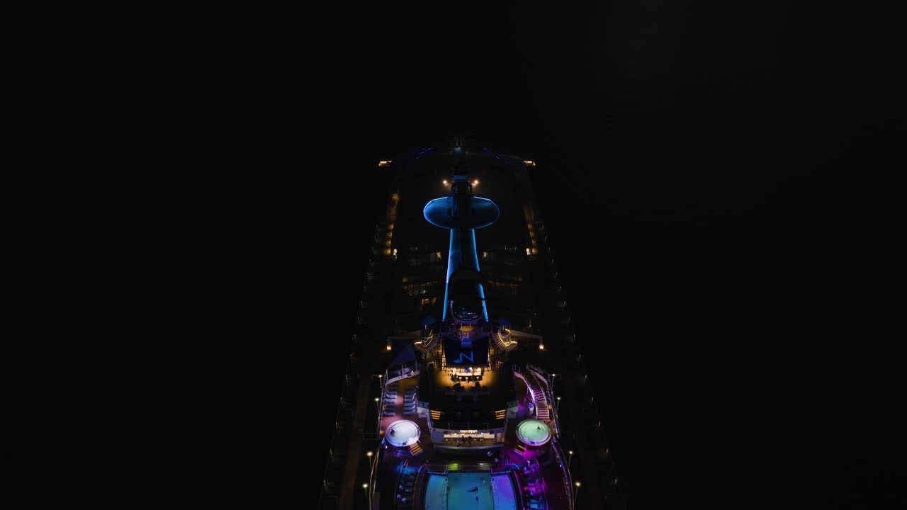 реверсивная съемка с беспилотника над палубой бассейна на большом круизном лайнере "квант морей" у берегов лахаины, гавайи, сша ночью